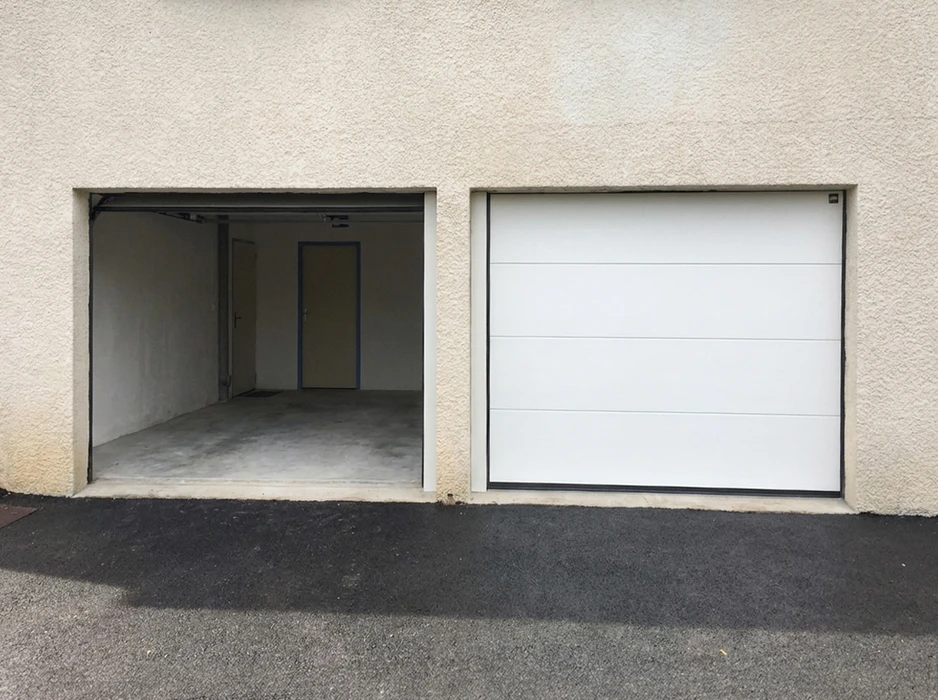 Façade de bâtiment résidentiel en enduit blanc, deux ouvertures de garage côte à côte